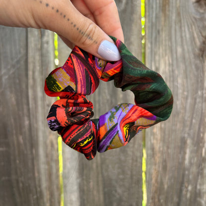 Colorful patterned scrunchie held by a hand against a wooden background