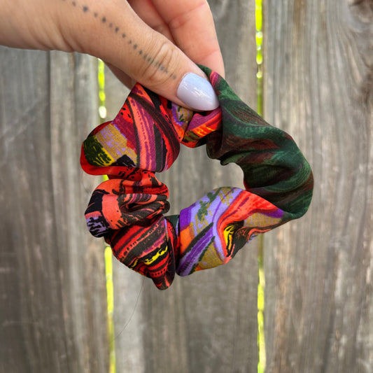 Colorful patterned scrunchie held by a hand against a wooden background