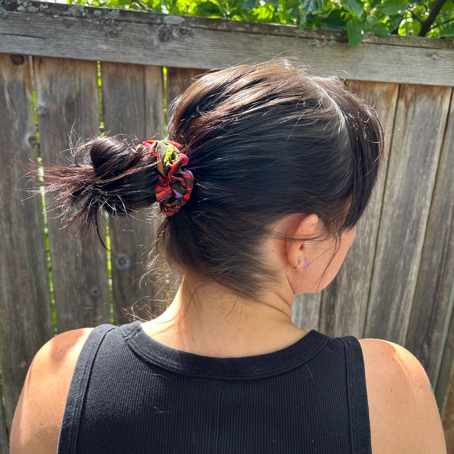Person with a ponytail wearing a black tank top outdoors