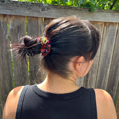 Person with a ponytail wearing a black tank top outdoors